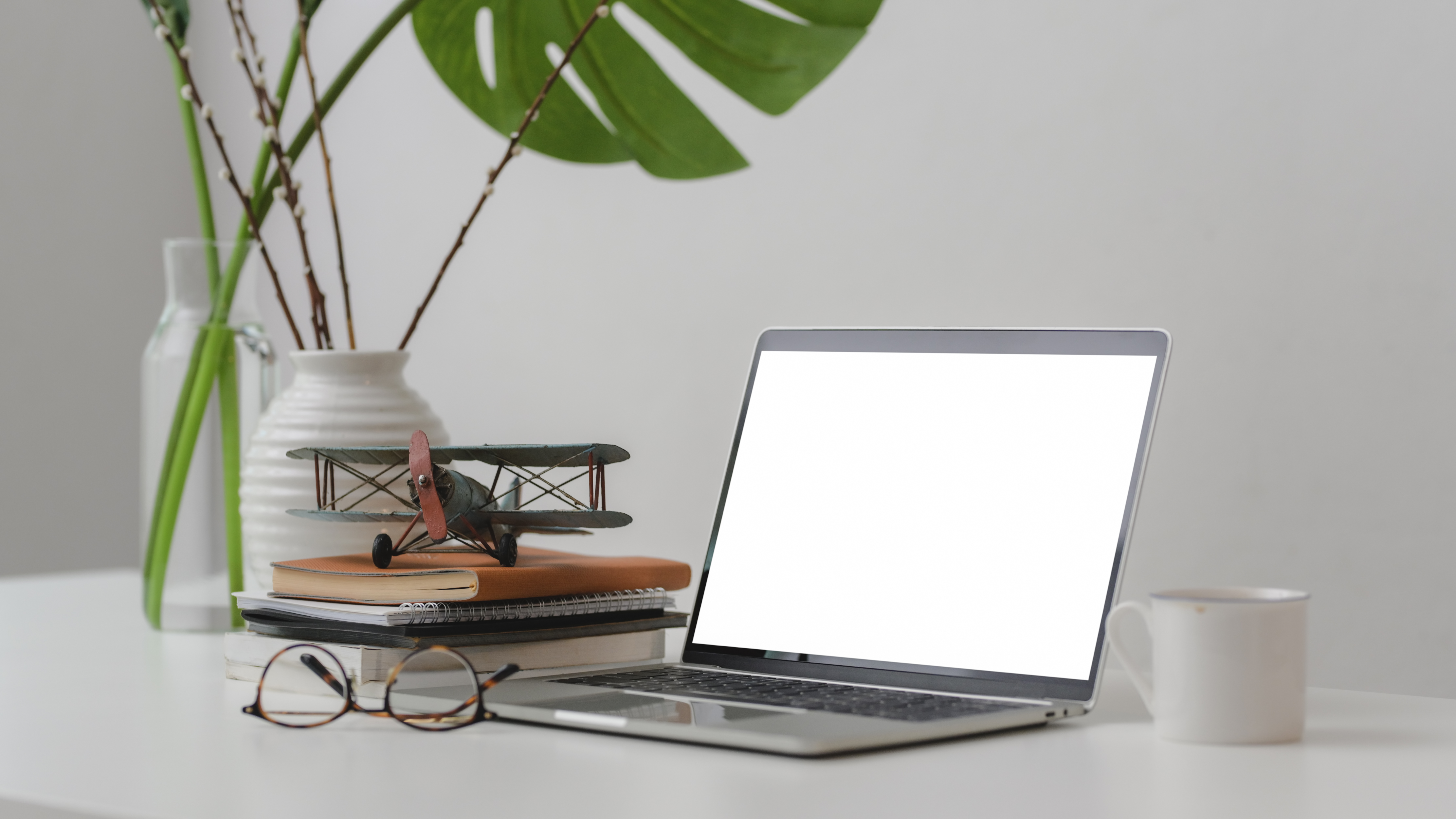 Cropped shot of trendy workspace with laptop, office supplies and decorations   on white desk with white wall background